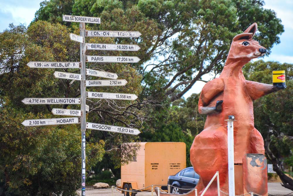 On the border of South and Western Australia a sign a show distances to the worlds major cities with a giant kangeroo looking on