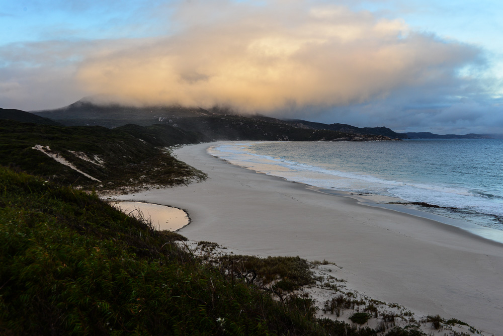 An image of Normans Beach with a cloud lit by the lowering sun.