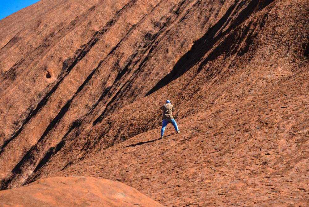 Image of a man taking a photo having climbed up the side of Uluru