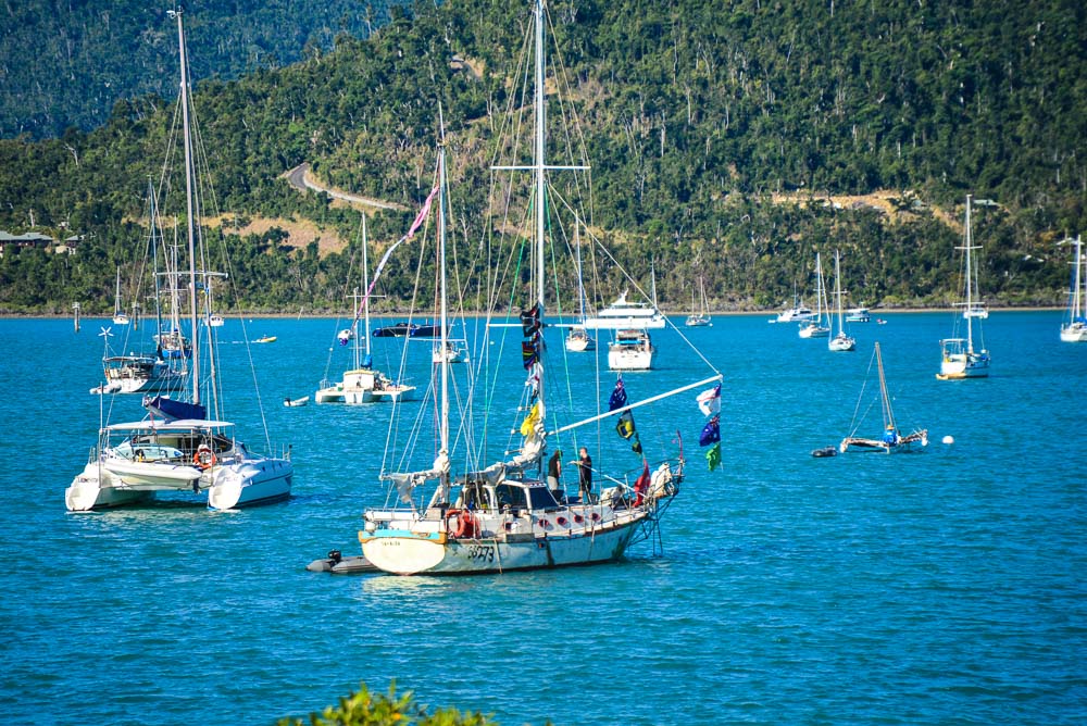 Image of a yatch in the harbour at Airlie Beach with lots of flags flying.