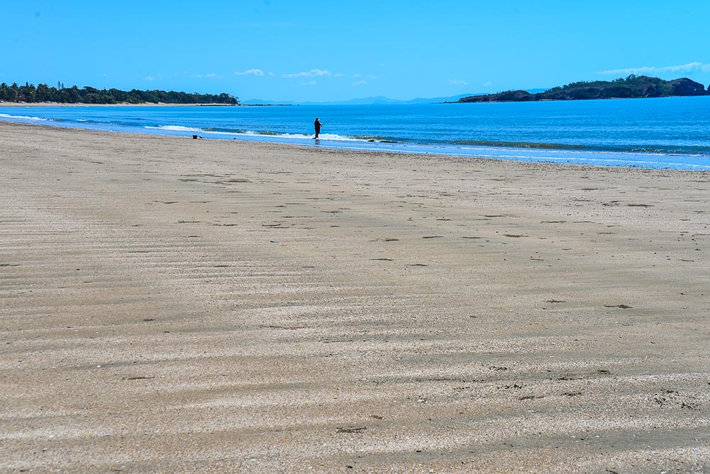 Image of a person fishing from the nearly deserted beach at Seaforth queensland.