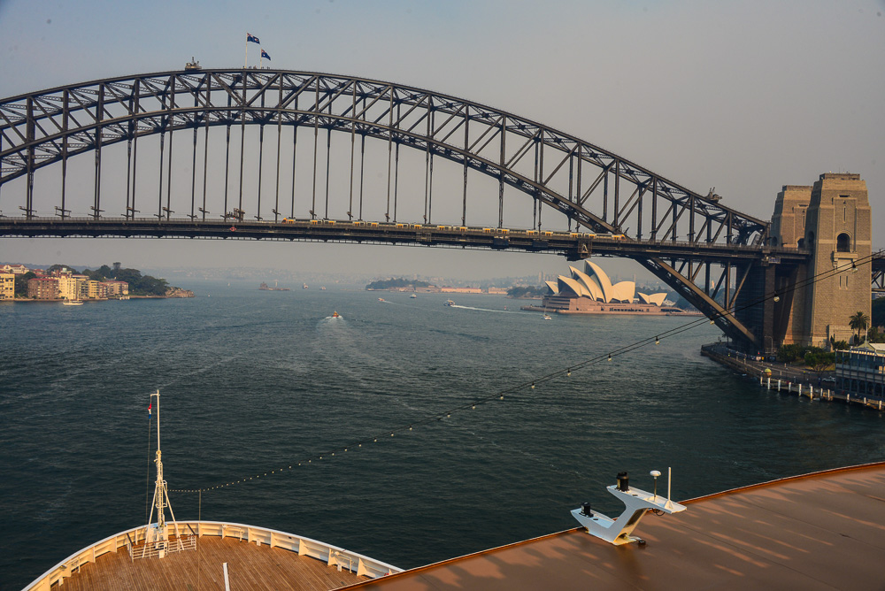 The Sydney Opera House appears under the Harbour Bridge in the smokey afternoon light